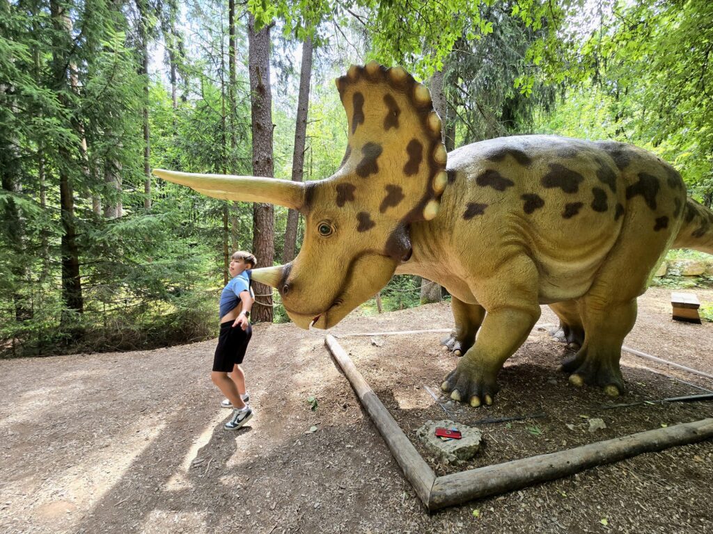 Triceratops-Skulptur im Dinosauriermuseum Altmühltal mit spielendem Kind. Spannendes Erlebnis für Kinder und Familien in Bayern.