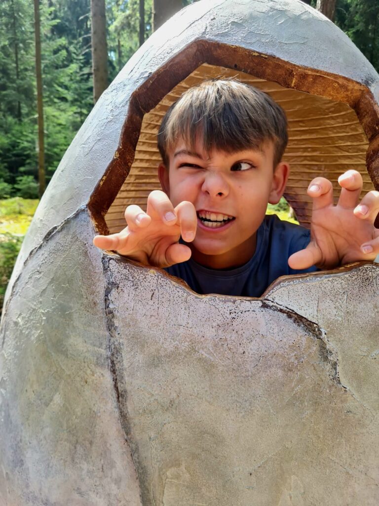 Kind steckt den Kopf durch ein überdimensionales Dinosaurier-Ei im Dinosauriermuseum Altmühltal. Spaßige Foto-Station für Kinder.