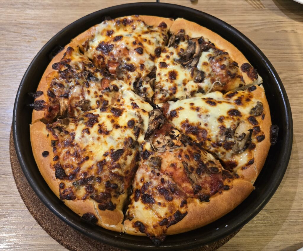 Champignon Pan Pizza bei Pizza Hut Nürnberg, goldbraun überbacken und in Stücke geschnitten.