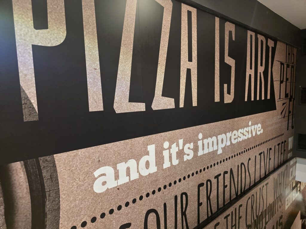 Wanddekoration bei Pizza Hut Nürnberg mit dem Schriftzug „Pizza is Art“.