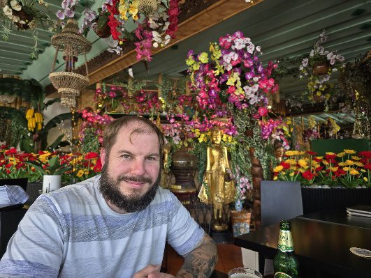 Gast im thailändischen Restaurant Rambutan in Garmisch-Partenkirchen, dekoriert mit Blumen und goldenen Statuen. Beliebtes Lokal für exotisches Essen in Bayern.