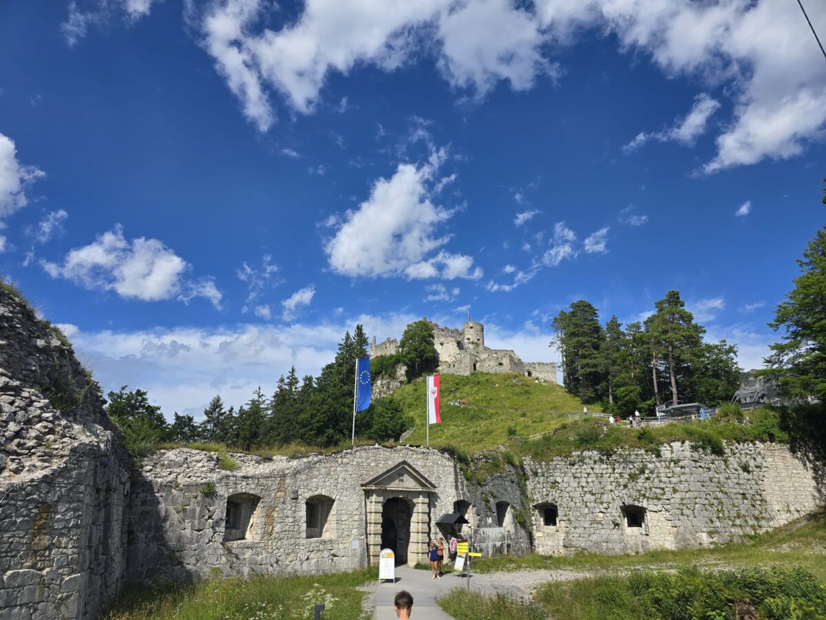 Blick auf die Burg Ehrenberg in Reutte, Tirol, mit strahlend blauem Himmel und grüner Landschaft.