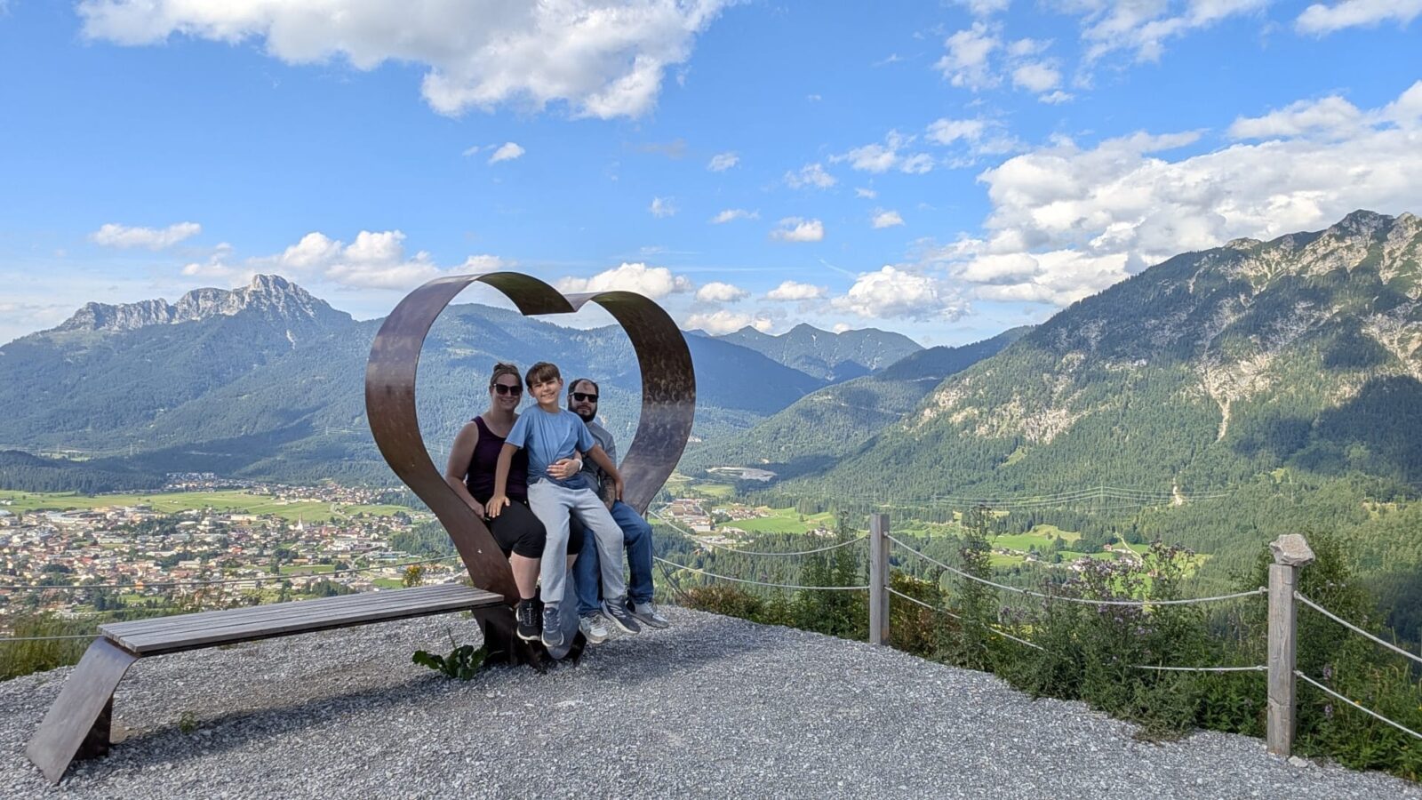 Familie sitzt auf der Herzbank oberhalb der Burgenwelt Ehrenberg mit Blick auf die Tiroler Berge.